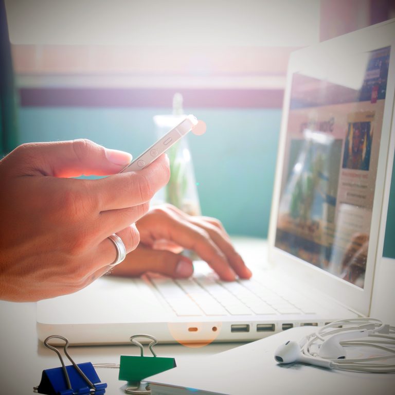 Man's hand holding smartphone and using laptop for online market
